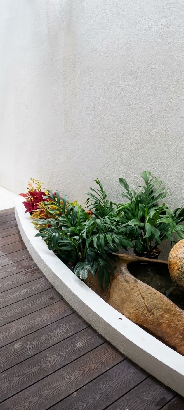 Deck: A curved bed of crotons and leafy plants, with a boulder. Landscaping by 54 Weng Thye Nursery & Landscapes.