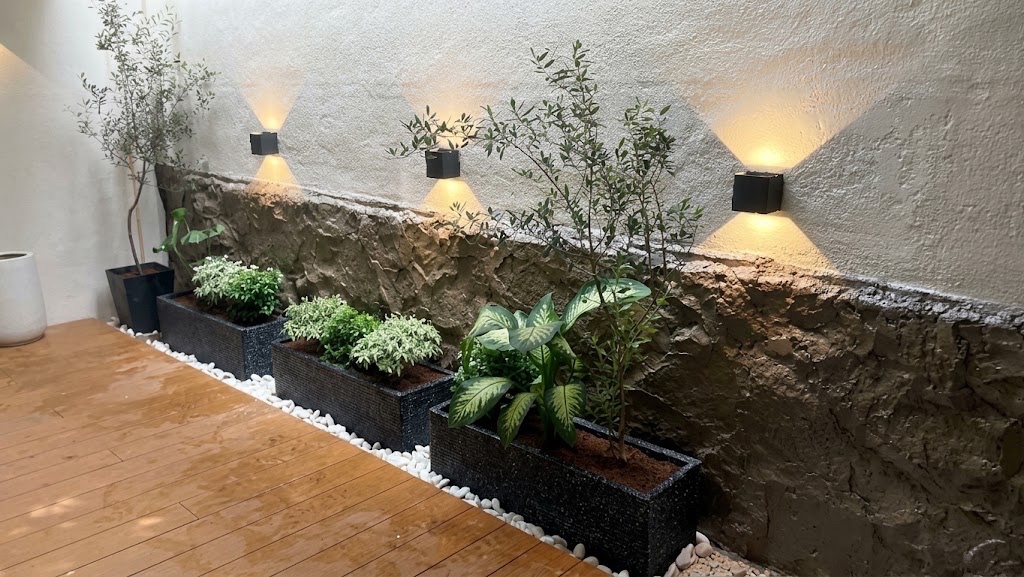 Courtyard deck: Planter boxes under wall lights, on a white pebble edge. Landscaping by 54 Weng Thye Nursery & Landscapes.
